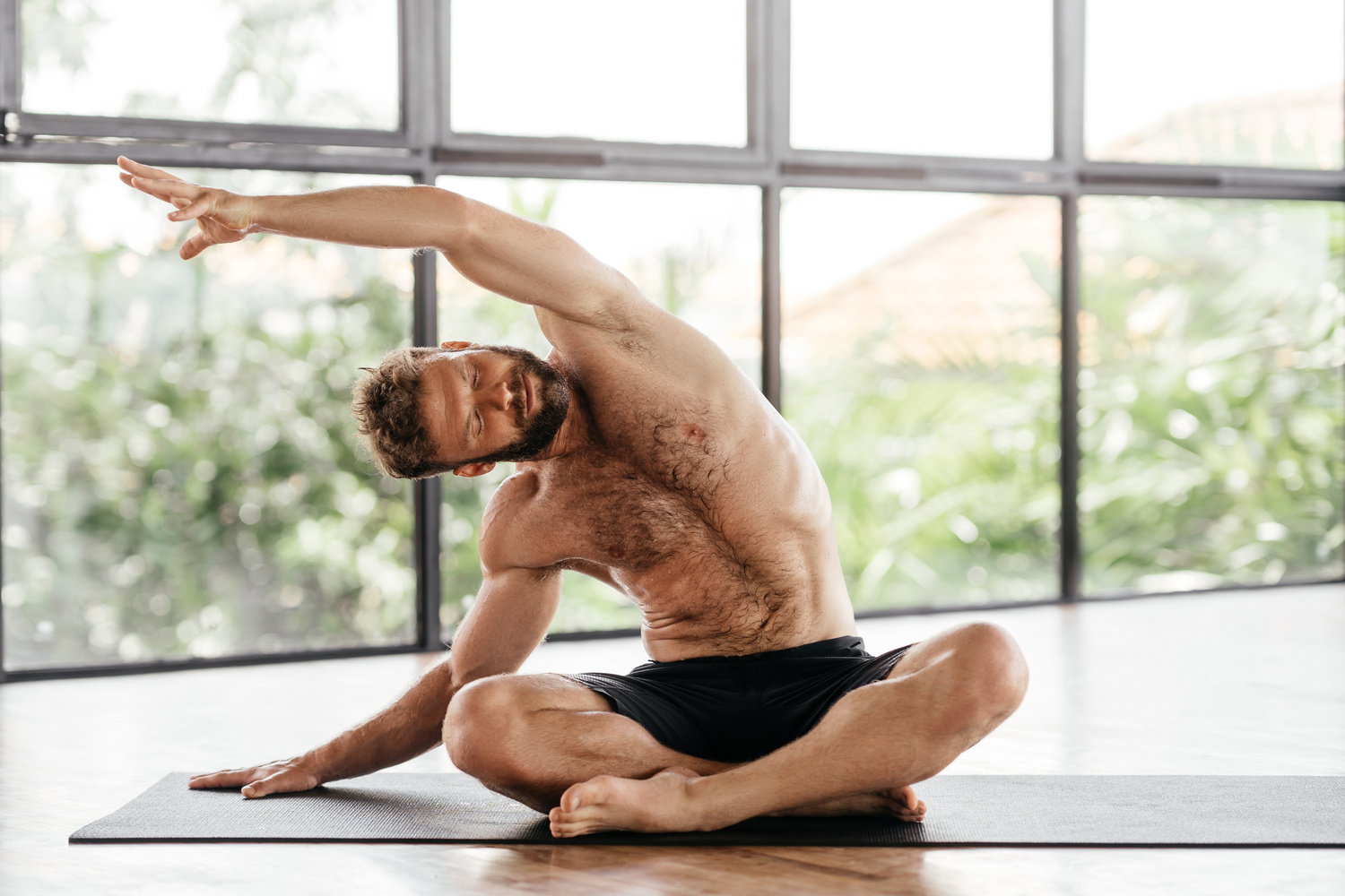 Yoga men workout in studio in front of a window